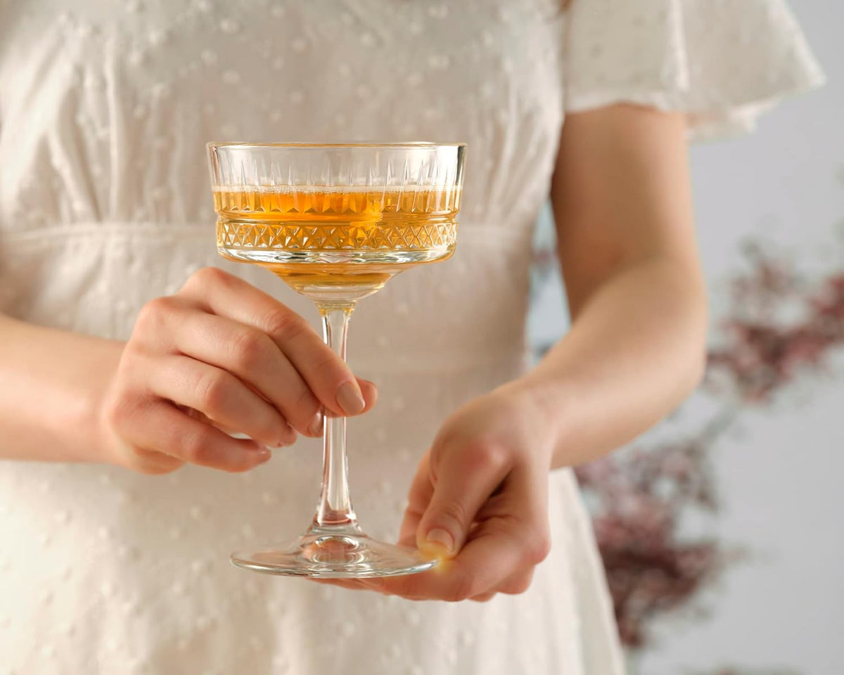 Person holding a glass of amber liquid with a blurred background