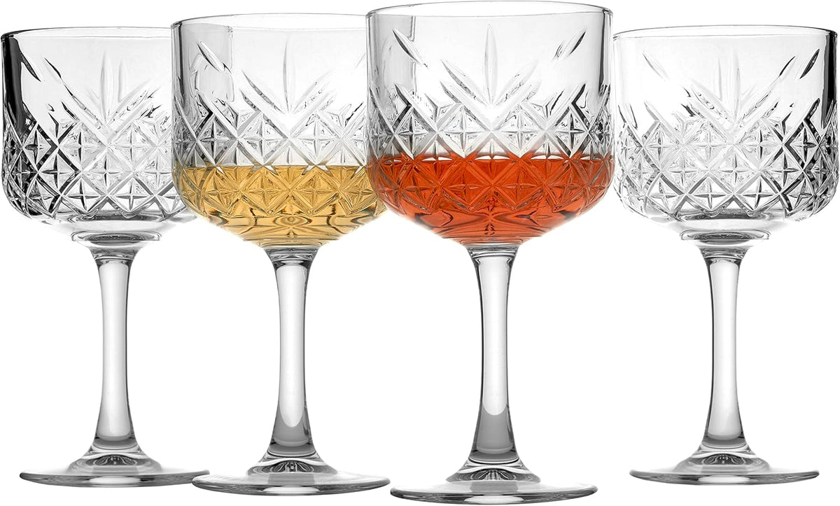 Set of four crystal wine glasses with different colored liquids on a white background