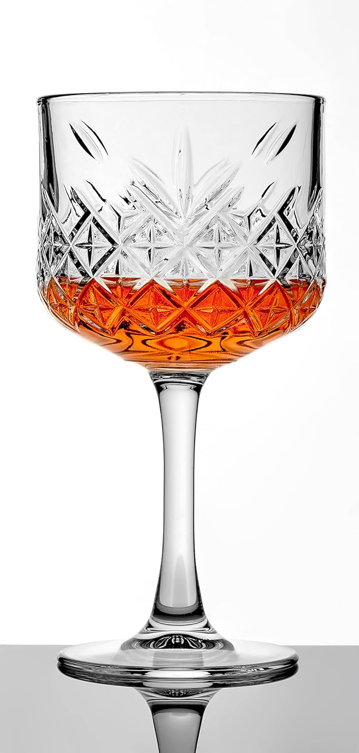 Crystal glass with cut patterns filled with a red-orange liquid on a white background